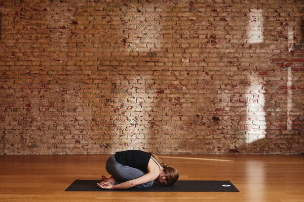 Ein Übender in der Kindeshaltung (Balasana) zur Entspannung des Rückens